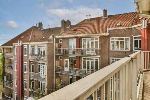 some houses in the city with red shutters and white balks on their windows, taken from an apartment balcony