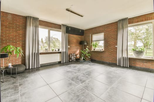a living room with red brick walls and grey tiles on the floor, there is an open window to the outside