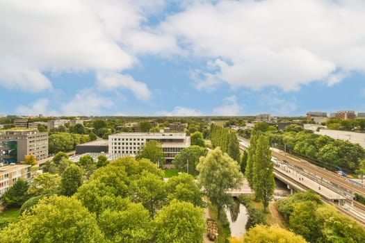 a city with trees and buildings in the fore - shot, taken from an aerial drone camera on a sunny day