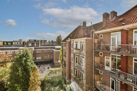 some buildings with balks on the top and trees in the bottom right hand corner, looking down to the street below