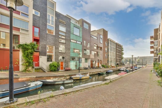 some boats parked on the side of a canal with buildings in the back ground and blue sky overhead above them