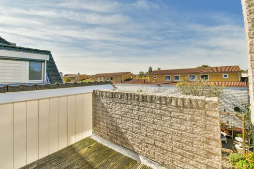 an outside area with some houses in the background and a blue sky above it, as seen from a window