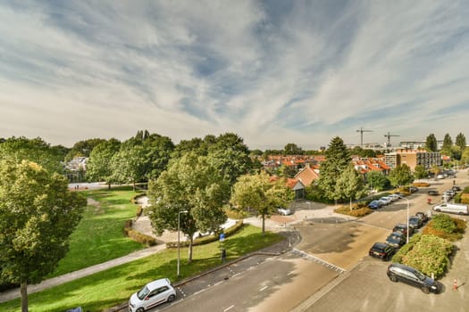 a city with cars parked on the street and trees in the fore - image taken from an aerial drone camera