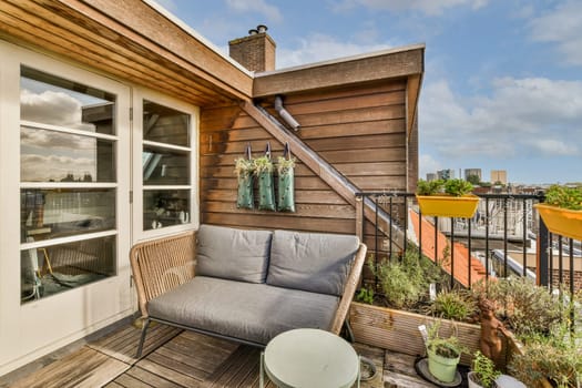 a balcony with chairs and plants on the decking area, looking out onto the street from an apartment building