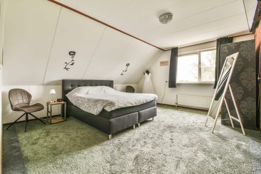 a bedroom with a bed, chair and tv on the wall in it's corner next to a window