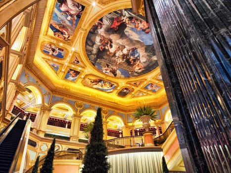 Macau, China - April 10, 2024: Visitors admire the stunning ceiling artwork and opulent design of Casino Venice Macau, creating a luxurious atmosphere in the evening.