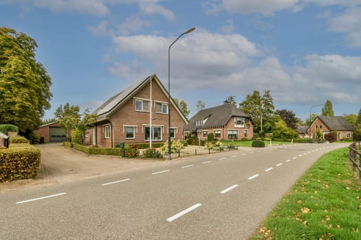 a street with houses in the background and trees on both sides, along an empty road that leads to a parking lot