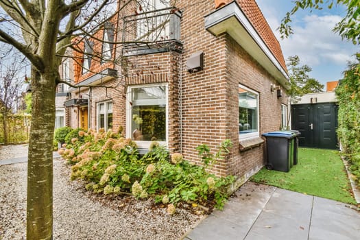 a house in the netherlands with brick walls and green grass, surrounded by plants and trees there is a hot tub
