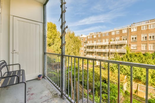 a balcony with chairs and trees in the foreground area, taken from an apartment window on a sunny day