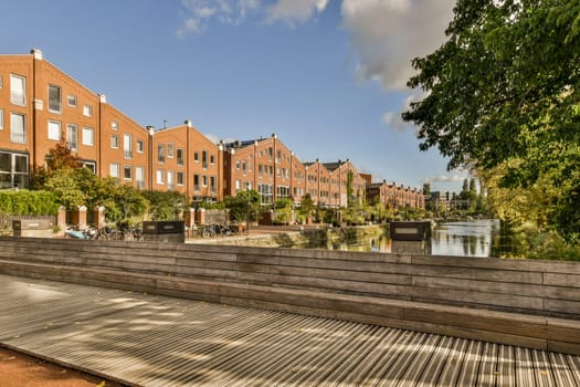 a bench in front of a row of brick apartment buildings on a sunny day with blue sky and white clouds