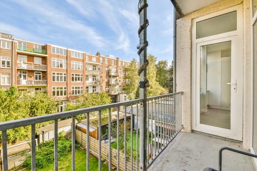 a balcony with trees and buildings in the background, taken from an apartment window looking out to the street below