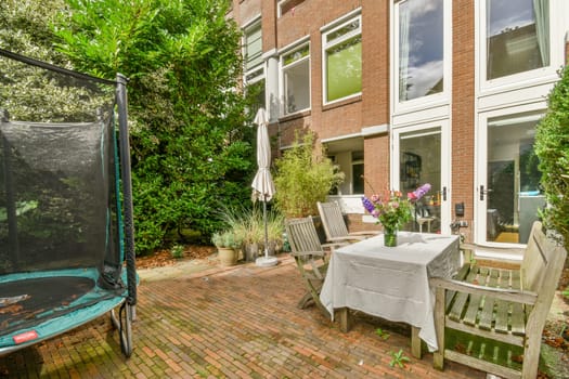 a patio with chairs, table and an umbrella on it's side door to the back of a house