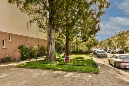 a tree in the middle of a street with cars parked on both sides and trees lining the side of the road