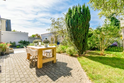 a backyard area with a table and chairs in the middle, surrounded by green trees on either side of the yard