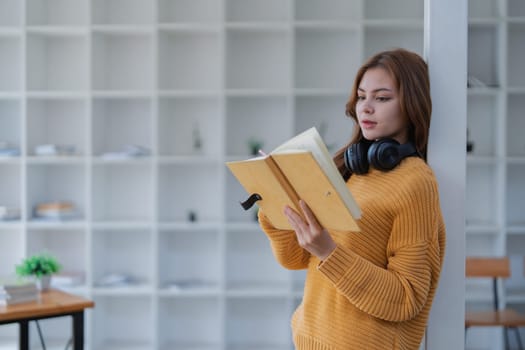 happy young woman with headphones is immersed in a book, happily learning.
