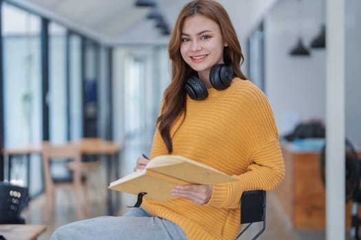 happy young woman with headphones is immersed in a book, happily learning.
