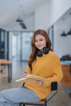 happy young woman with headphones is immersed in a book, happily learning.