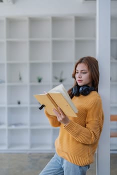 happy young woman with headphones is immersed in a book, happily learning.