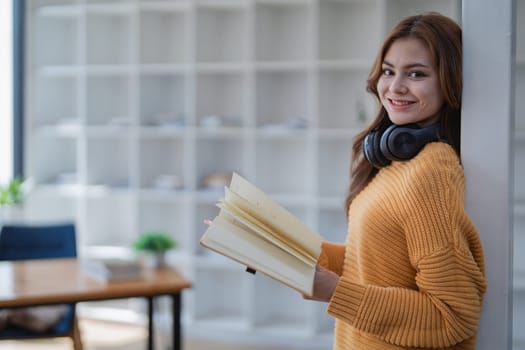 happy young woman with headphones is immersed in a book, happily learning.