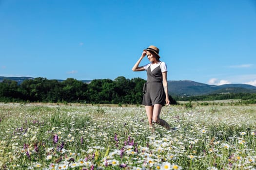 Beautiful woman in dress picking flowers in a field of daisies