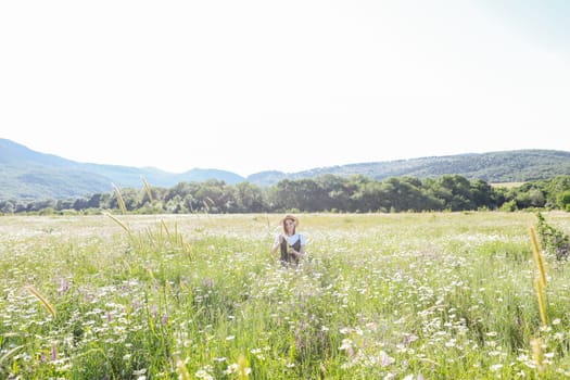 Beautiful woman in dress sitting with flowers in a field of daisies