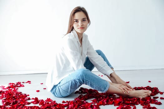 woman sitting on the floor with red rose petals