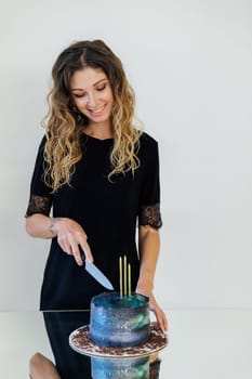 Beautiful woman cutting birthday cake and smiling