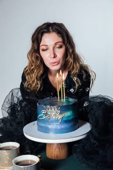 Beautiful woman blowing out candles on birthday cake