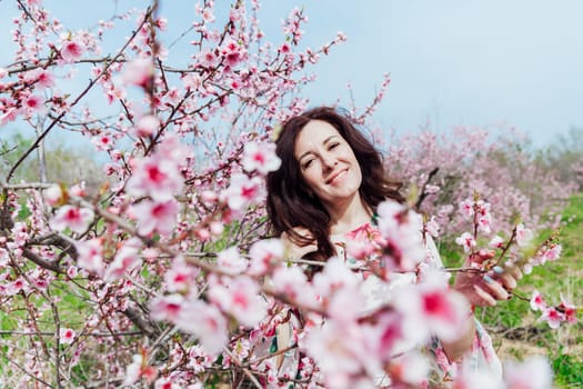 Brunette woman smiling in flower dress in spring blooming garden