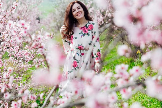 Brunette woman walking in flower dress in spring blooming garden