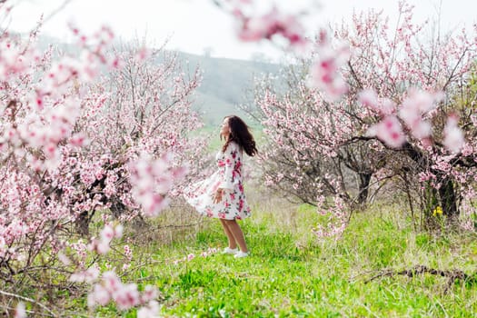 Brunette woman walking in flower dress in spring blooming garden