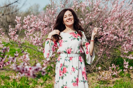 Brunette woman walking in flower dress in spring blooming garden