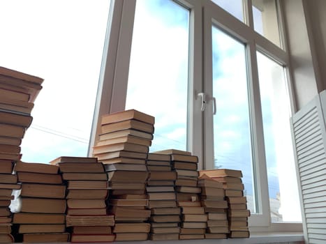 many stacks of books for learning at the window of the university library