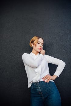 Portrait of a beautiful slender woman fashionably in jeans on a dark background