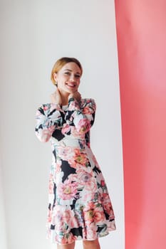Beautiful fashion blonde woman in summer dress with flowers on pink background smiling