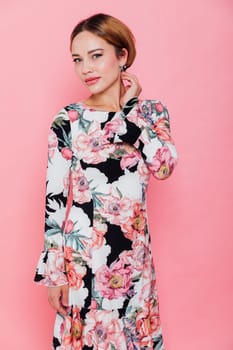 Beautiful fashion blonde woman in summer dress with flowers on pink background smiling