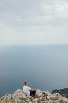 Man hiking looking landscape at sky with clouds and green forest from mountain top