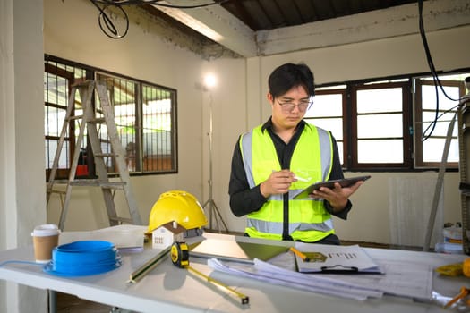 Engineer using digital tablet to review construction plans.