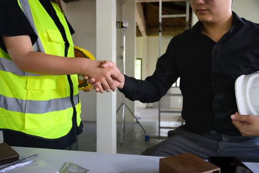 Architects shaking hands at a building site with successful collaboration in renovation project.