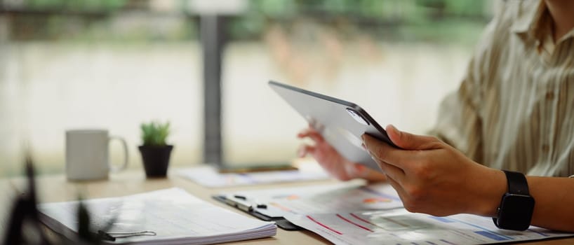Businessman using digital tablet and reviewing reports at desk.