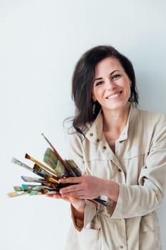 Brunette artist holding brushes in her hands to paint paintings