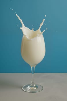 Glass with milk splash on blue background, AI generation.