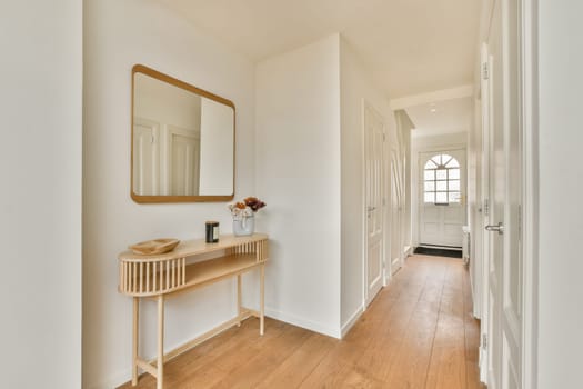 A sleek and bright hallway featuring a wooden floor, white walls, a stylish mirror, and minimal decor, radiating a fresh, airy ambiance.