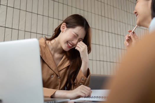 A university student laughs while studying, cherishing the humorous side of education as she interacts with her study partner.