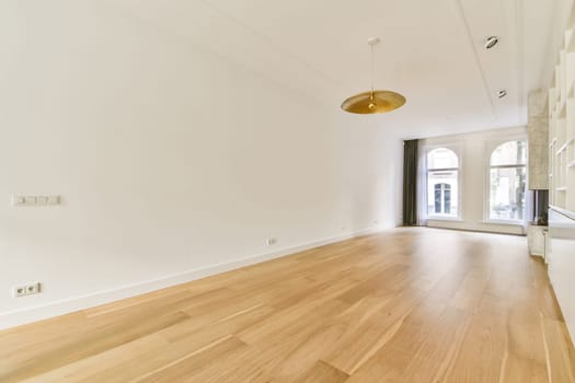 A bright and airy room featuring wooden flooring, high ceilings, and large windows that let in natural light, creating an inviting and open atmosphere.
