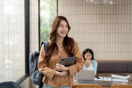 Carrying a tablet, a motivated student walks into a modern cafe, excited to engage in productive study sessions and networking.