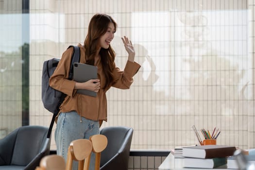 A happy student, carrying her backpack and tablet, joyfully greets her peers as she arrives at a study session, embodying enthusiasm and teamwork.