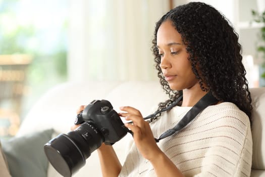 Serious black photographer at home checking dslr camera