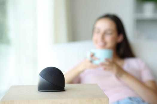 Happy woman is relaxing and drinking coffee with smart speaker at home