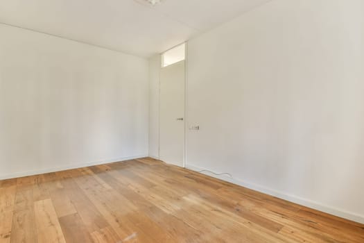 A spacious, empty room featuring light-colored walls and wooden flooring, showcasing a minimalist interior design that emphasizes simplicity and openness.